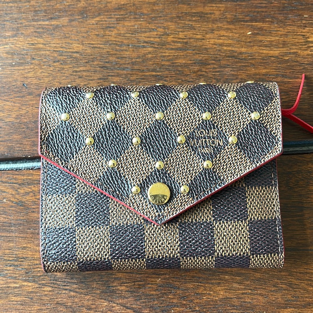 LOUIS VUITTON
Damier Ebene Studded Victorine Wallet Cherry